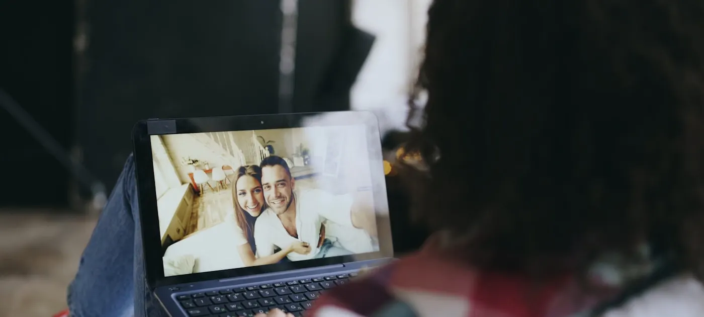 Woman video calls couple on laptop outdoors.